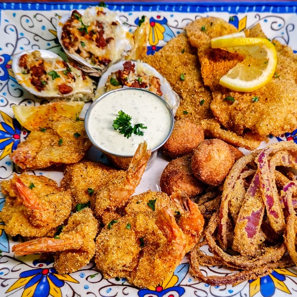A vibrant platter of fried seafood, including shrimp, oysters, fish, hush puppies, and onion rings.